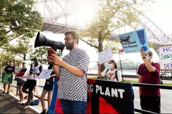Zohran Mamdani advocates against a gas plant, wearing an accessible smart casual outfit.